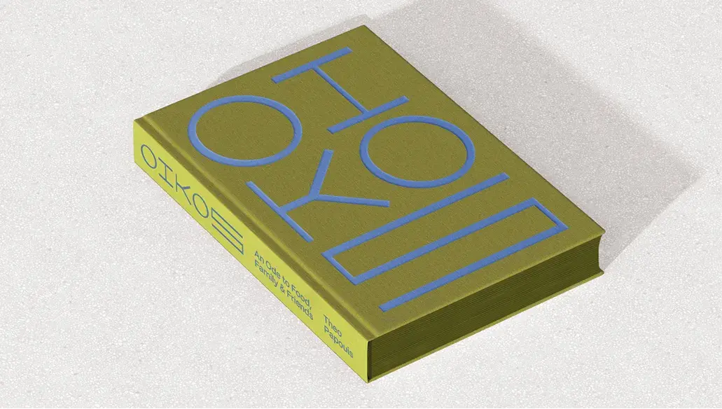 Olive green book with bold, light blue geometric text on the cover and spine, placed on a neutral surface.