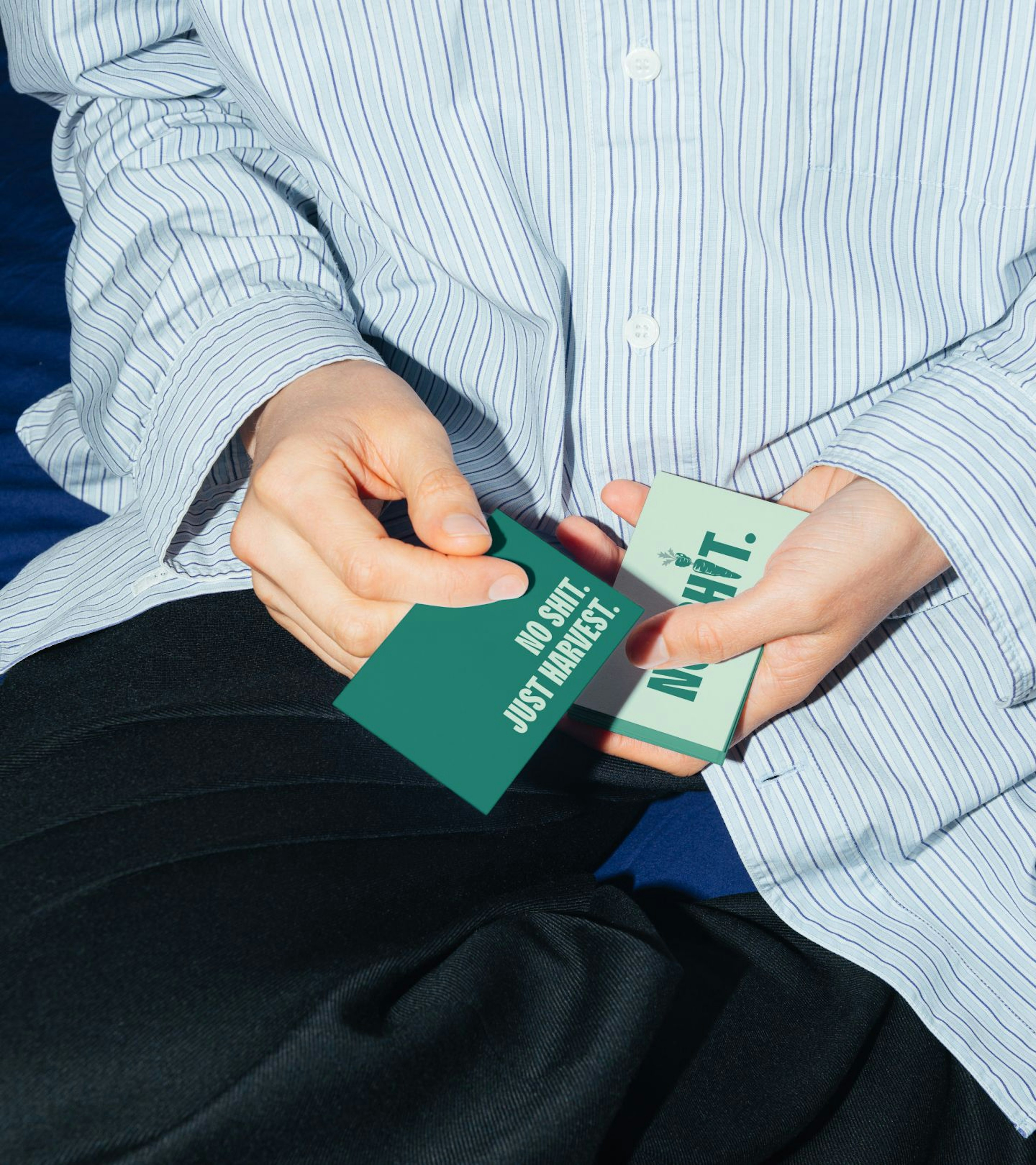 An image of someone wearing a blue blouse holding two business cards