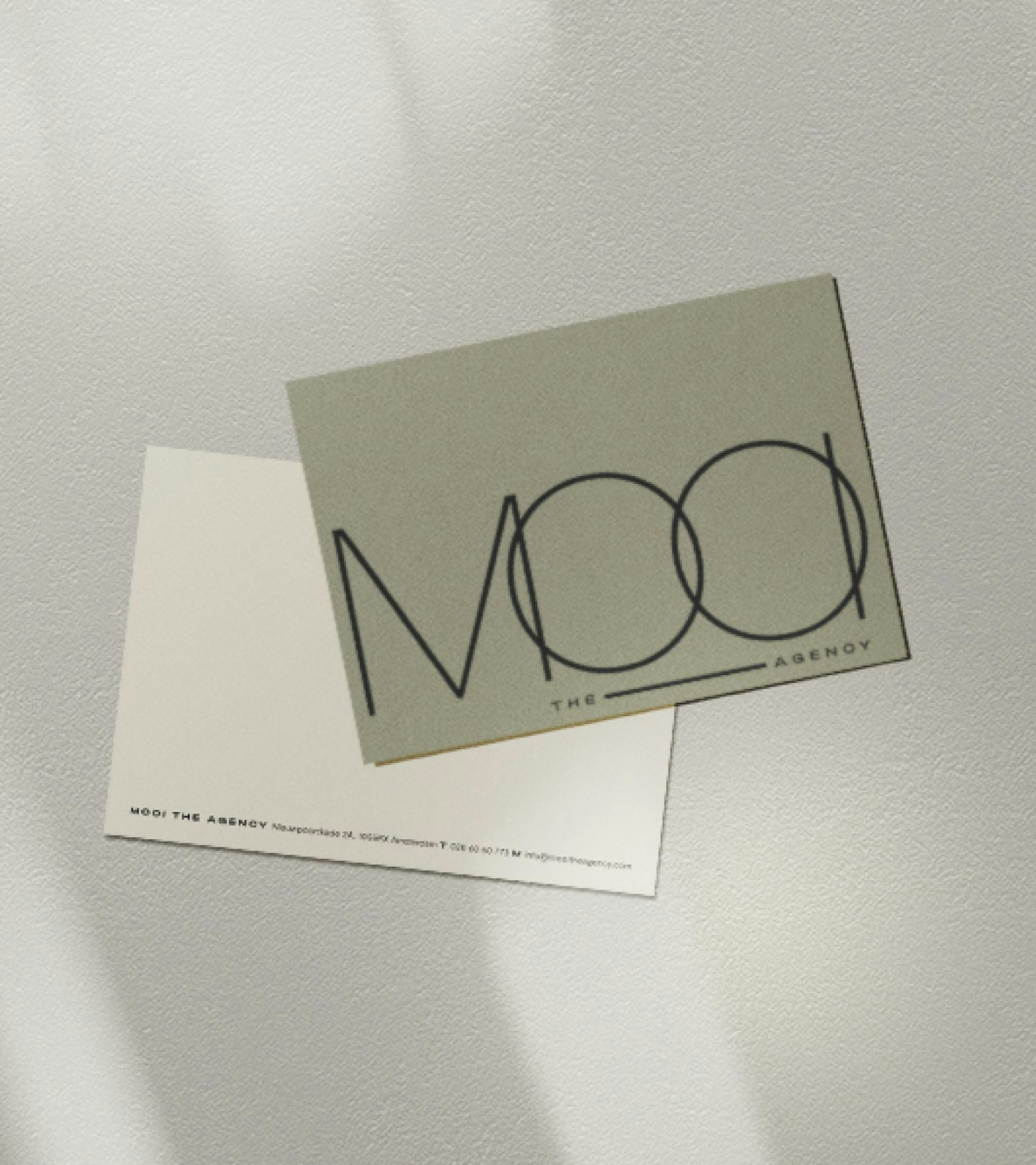 A gray background with two business cards with the logo and details of MOOI the Agency