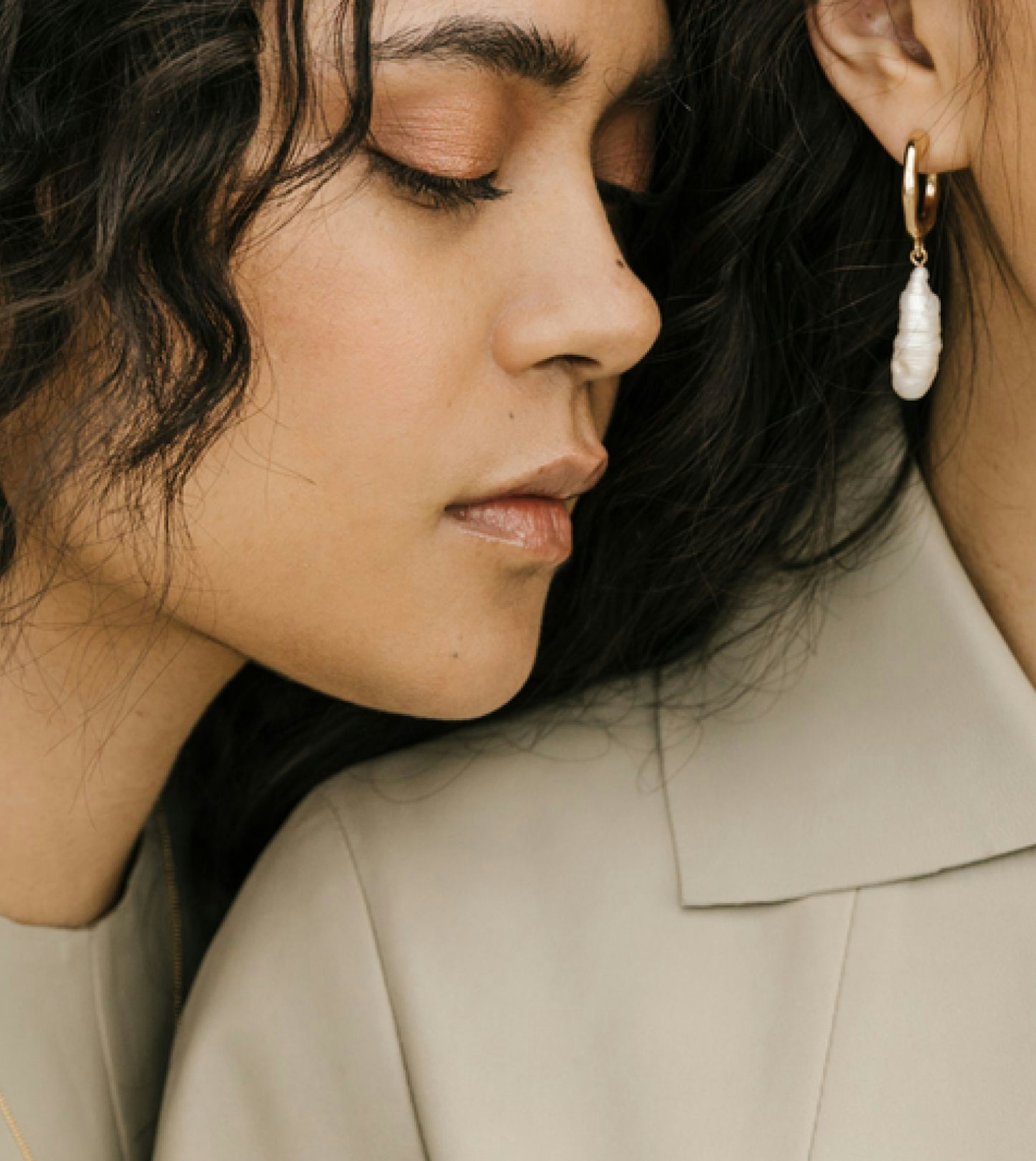 An image of two women wearing light-colored clothing. One woman leans on the other woman and has her eyes closed