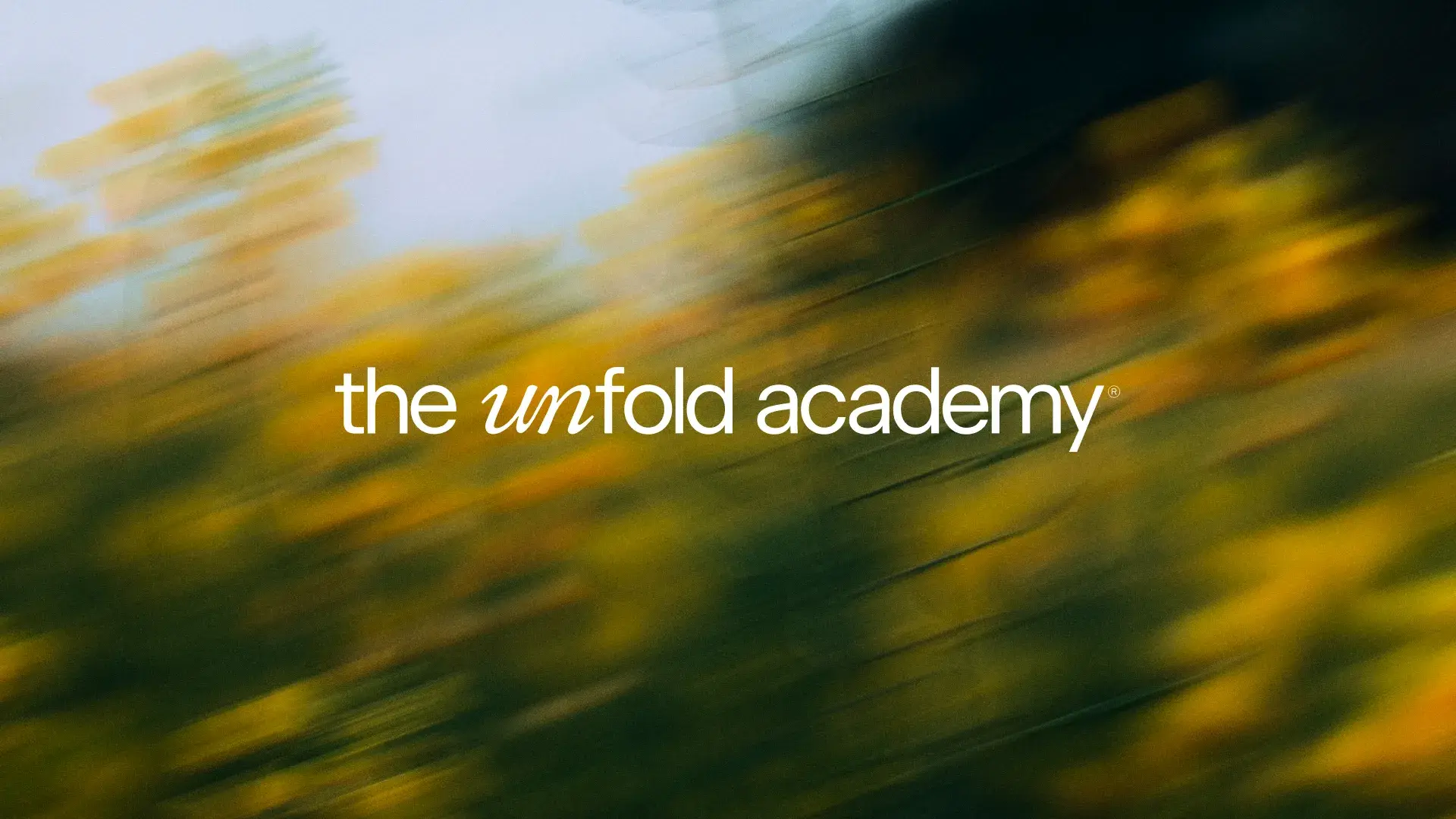 Blurred yellow flowers with text "the unfold academy" in white, centered over the image.