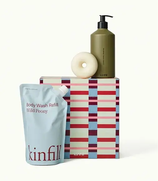 Kinfill body wash set featuring a Wild Peony refill, olive-green pump bottle, round soap, and patterned box.